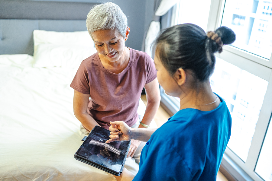 Caregiver assisting senior woman with tablet