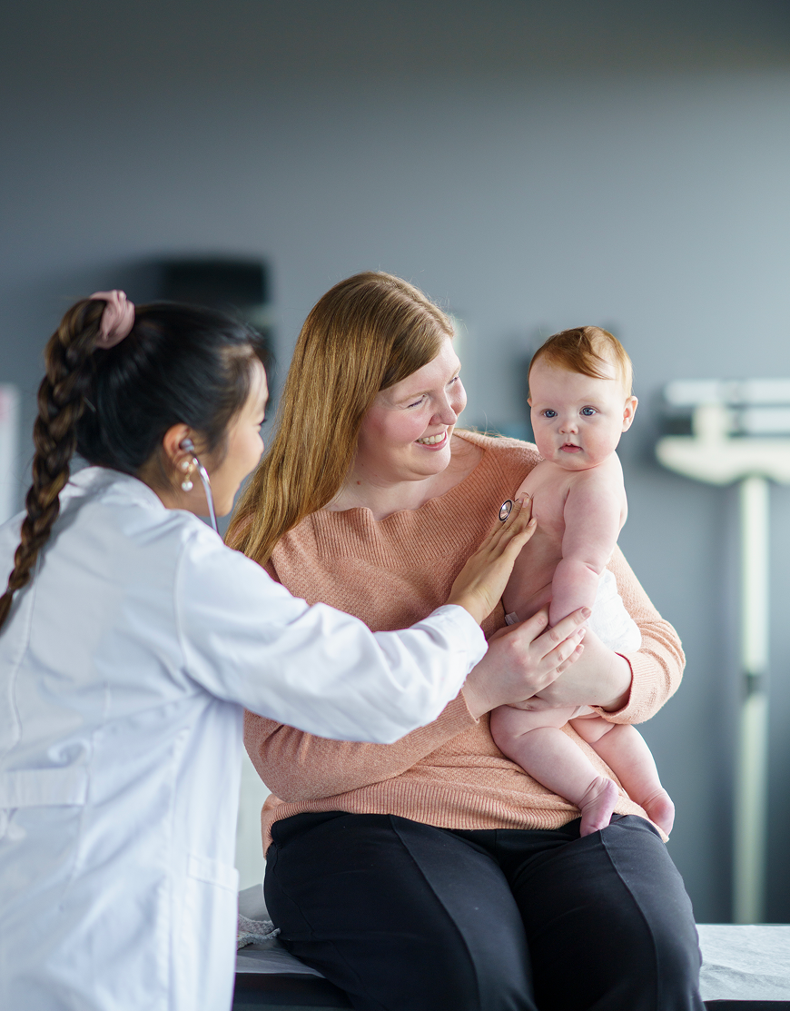 Doctor examining baby held by mother