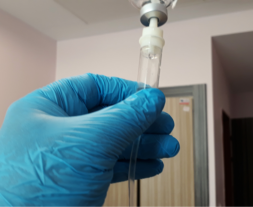 Gloved hand holding IV drip tube