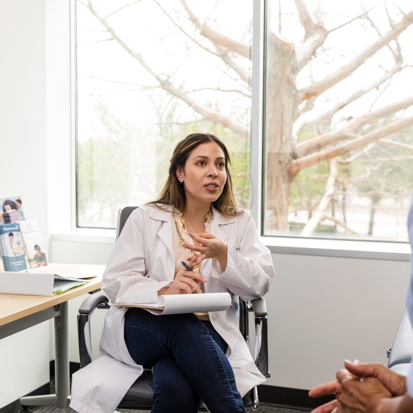 The female doctor gestures while explaining to her patient about the medication changes she wants to try.